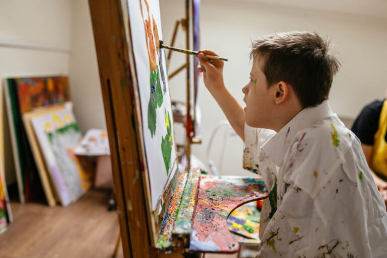 menino com síndrome de down pintando uma tela