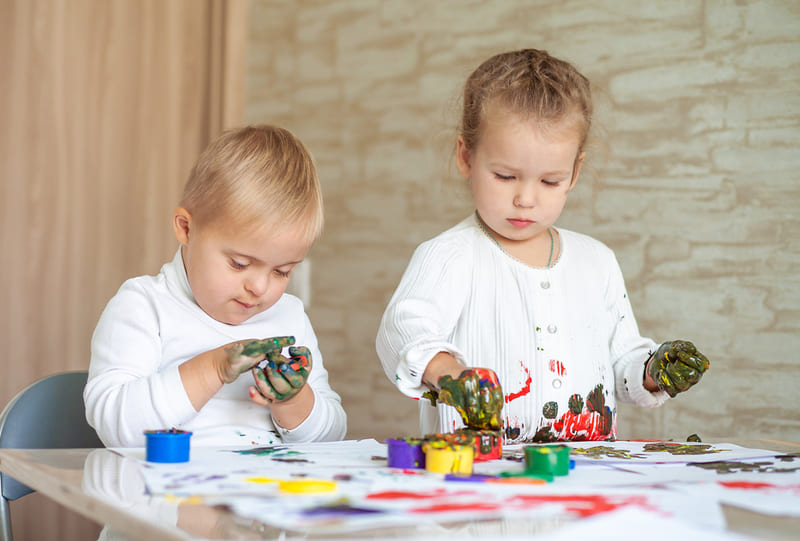 bebês brincando de pintar com a mão