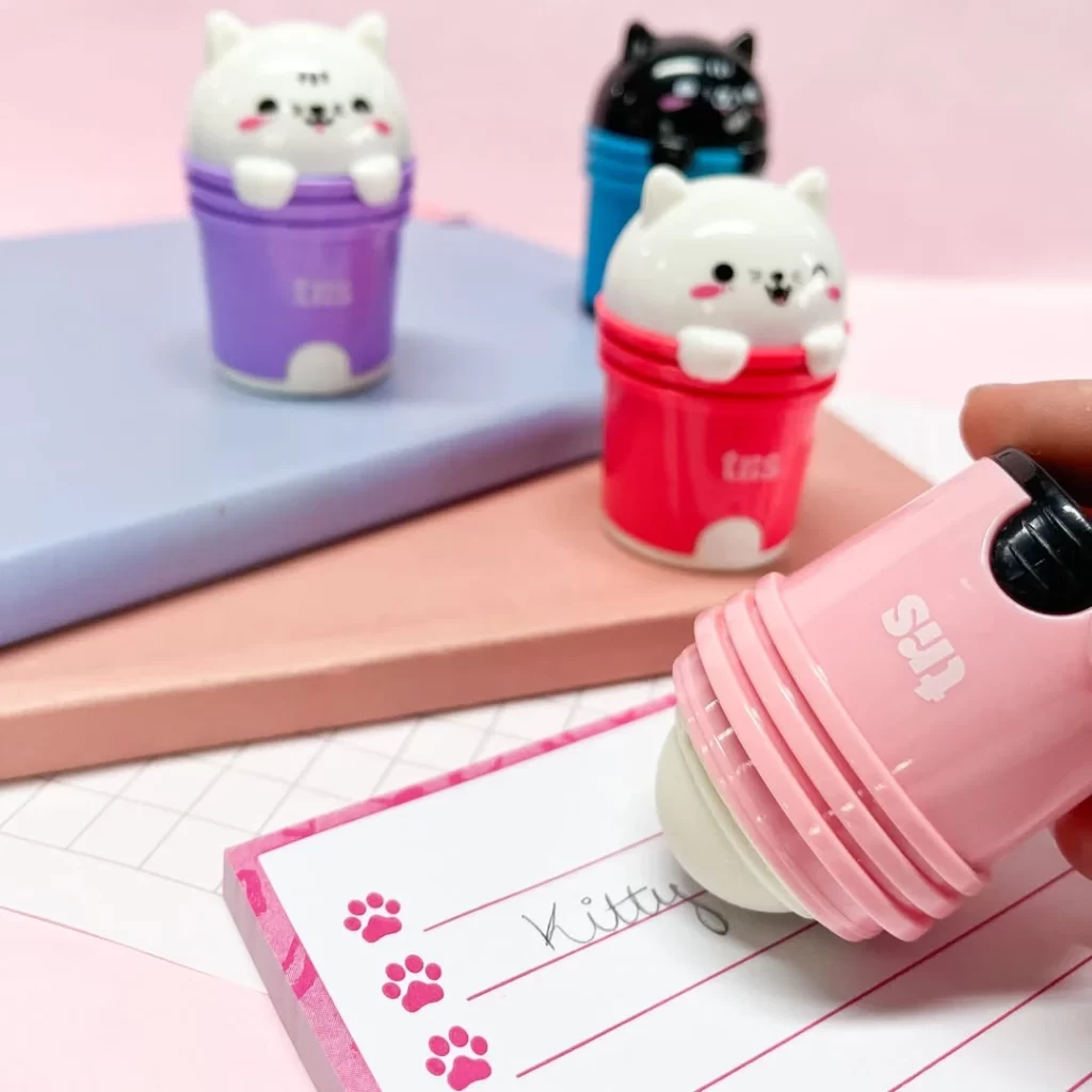 Conjunto de itens de papelaria criativa, como canetas de mesa decoradas com personagens de gatos fofos e coloridos, ideal para anotações ou decoração de papelaria.