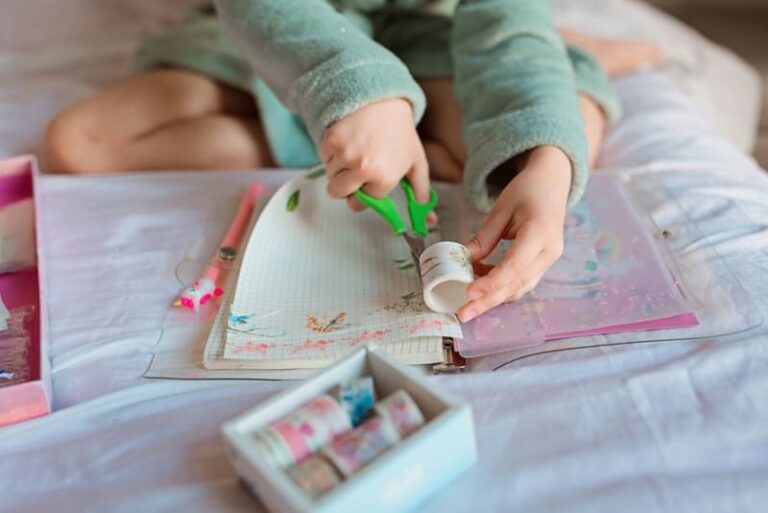 Menina customizando notebook com fita adesiva e tesoura na mão