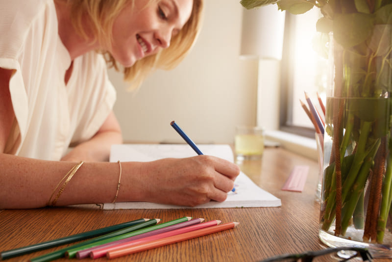 Mulher sorridente pintando desenhos em livro de colorir