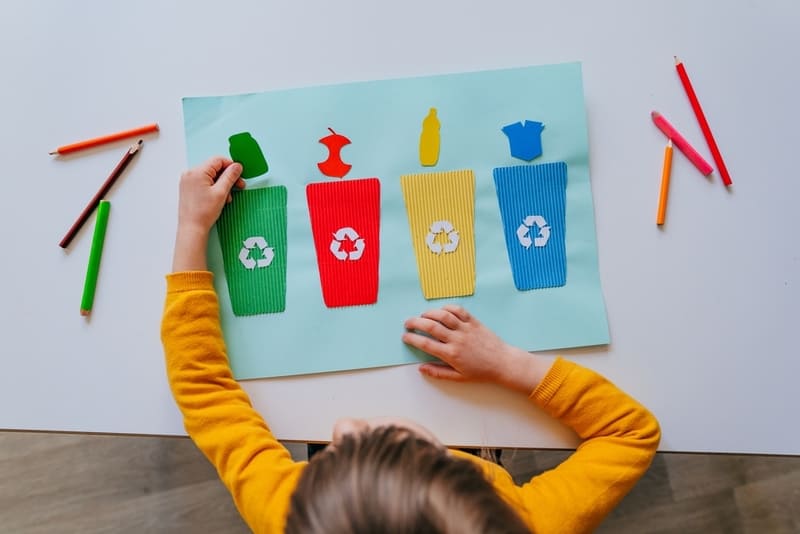 Criança criando cartaz com colagem sobre reciclagem