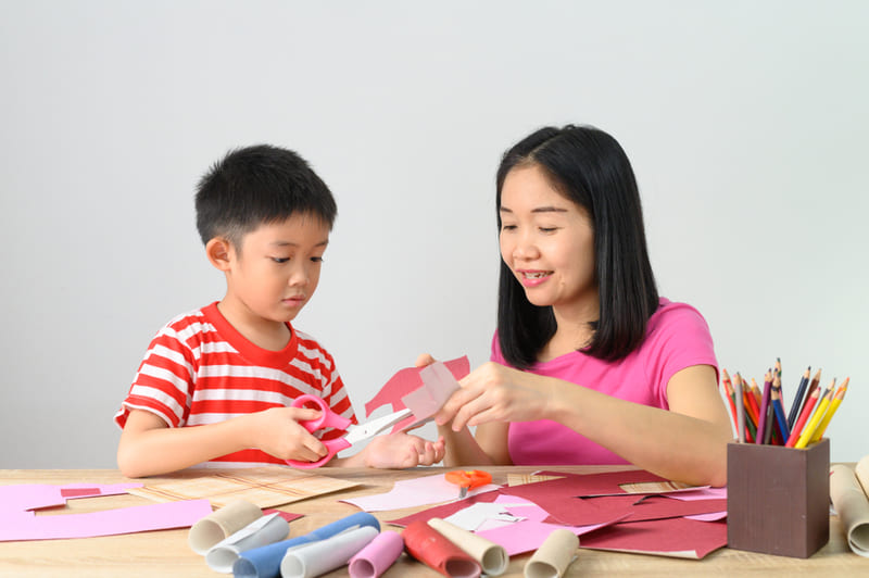 Mulher e criança cortando papel colorido