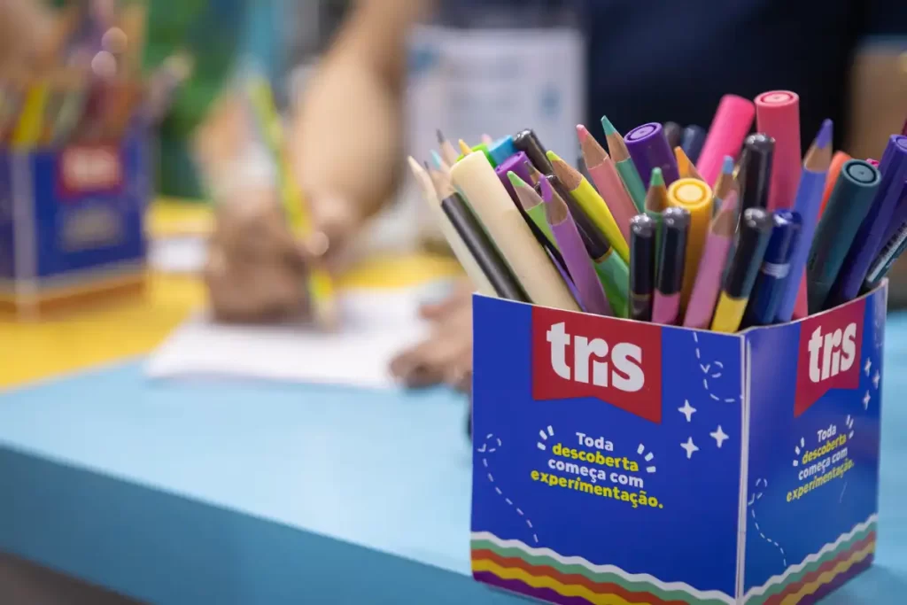 Caixa com lápis de cor e canetas da marca Tris.