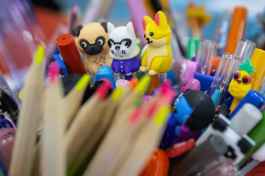 Diversos tipos de canetas e lápis coloridos, com personagens de cachorros de plástico.