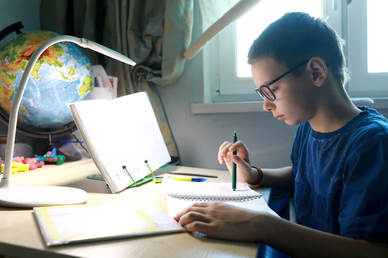 Jovem estudando com livros e cadernos na mesa