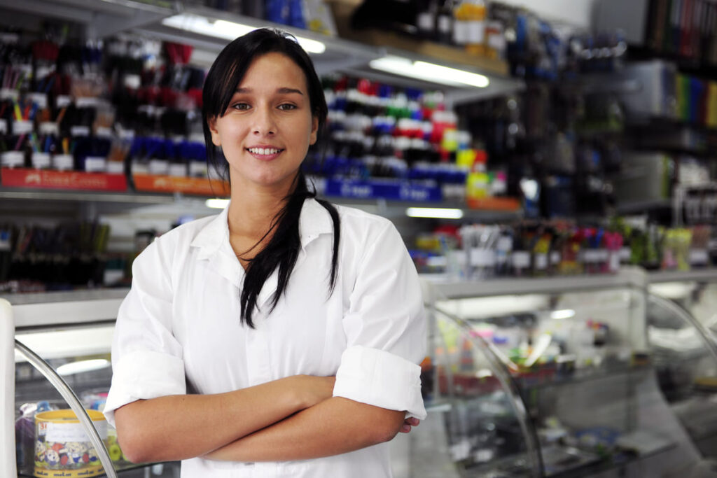 Mulher sorridente de braços cruzados em papelaria