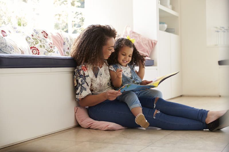 Criança no colo da mãe lendo um livro