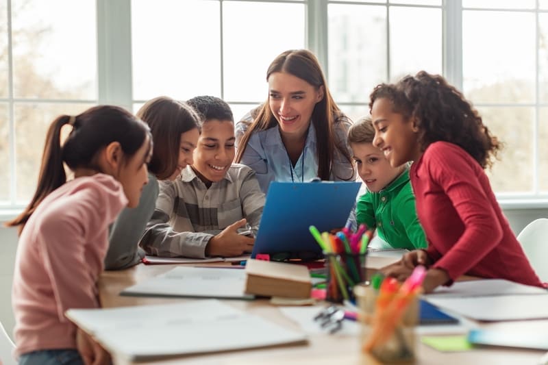 Crianças sorridentes conversando com professora em sala de aula