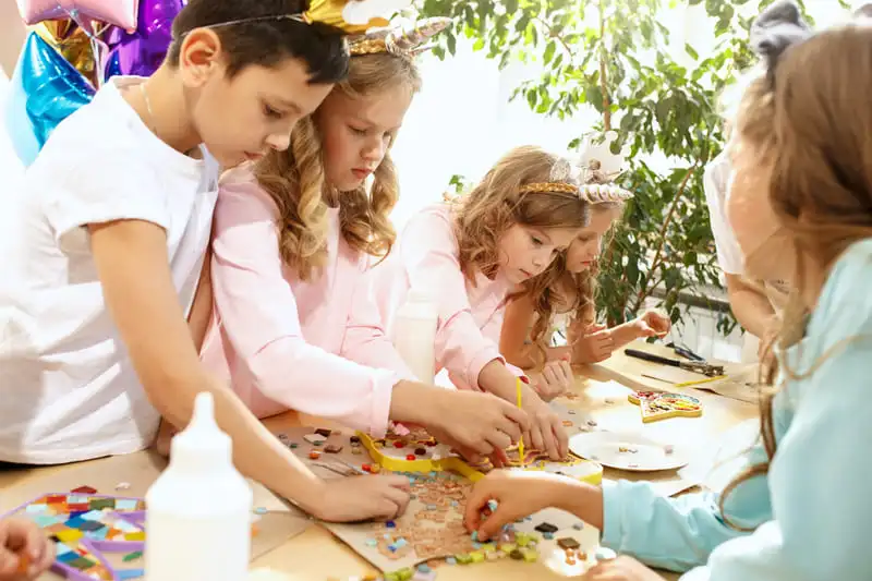 Crianças brincando de arte com papelão e purpurina no dia das crianças