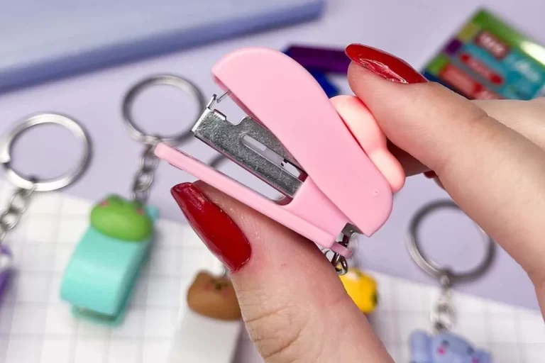 Grampeador pequeno rosa em mãos, destacando sua funcionalidade e design compacto, ideal para escritório ou uso pessoal.