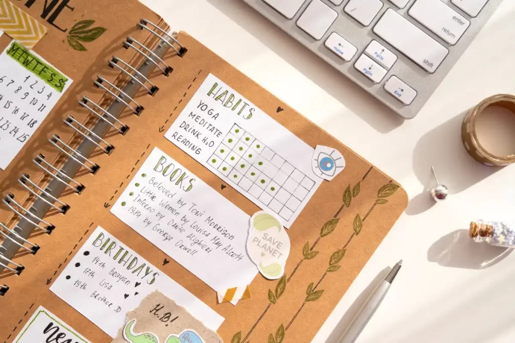 Caderno com anotações sobre hábitos, incluindo yoga, meditação e leitura, rodeado por materiais de escritório.
