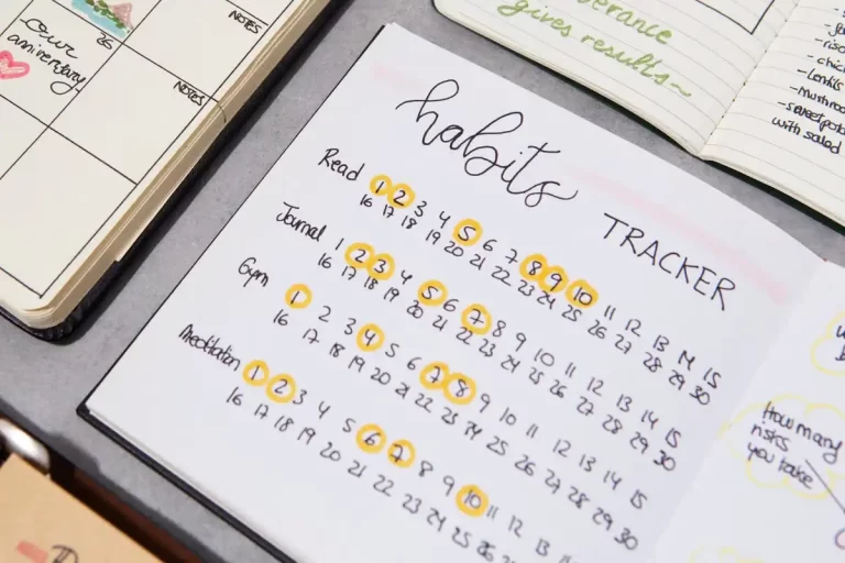 Caderno aberto mostrando um habit tracker com seções para leitura, diário, ginásio e meditação. Estilo de organização em bullet journal para acompanhamento diário.