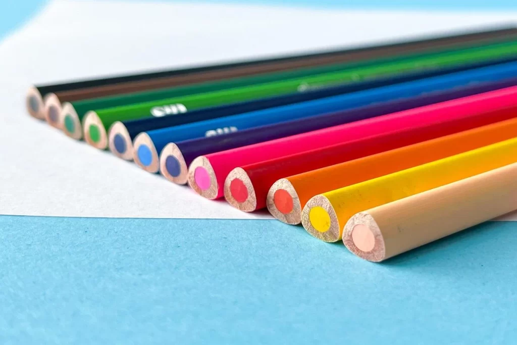 Imagem colorida com lápis de cor organizados em uma superfície azul.
