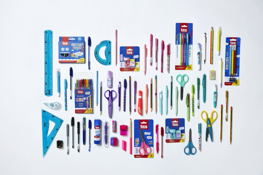Arranjo organizado de itens de papelaria, incluindo lápis, canetas, tesouras, réguas, borrachas e cadernos, ideal para estudantes e professores.
